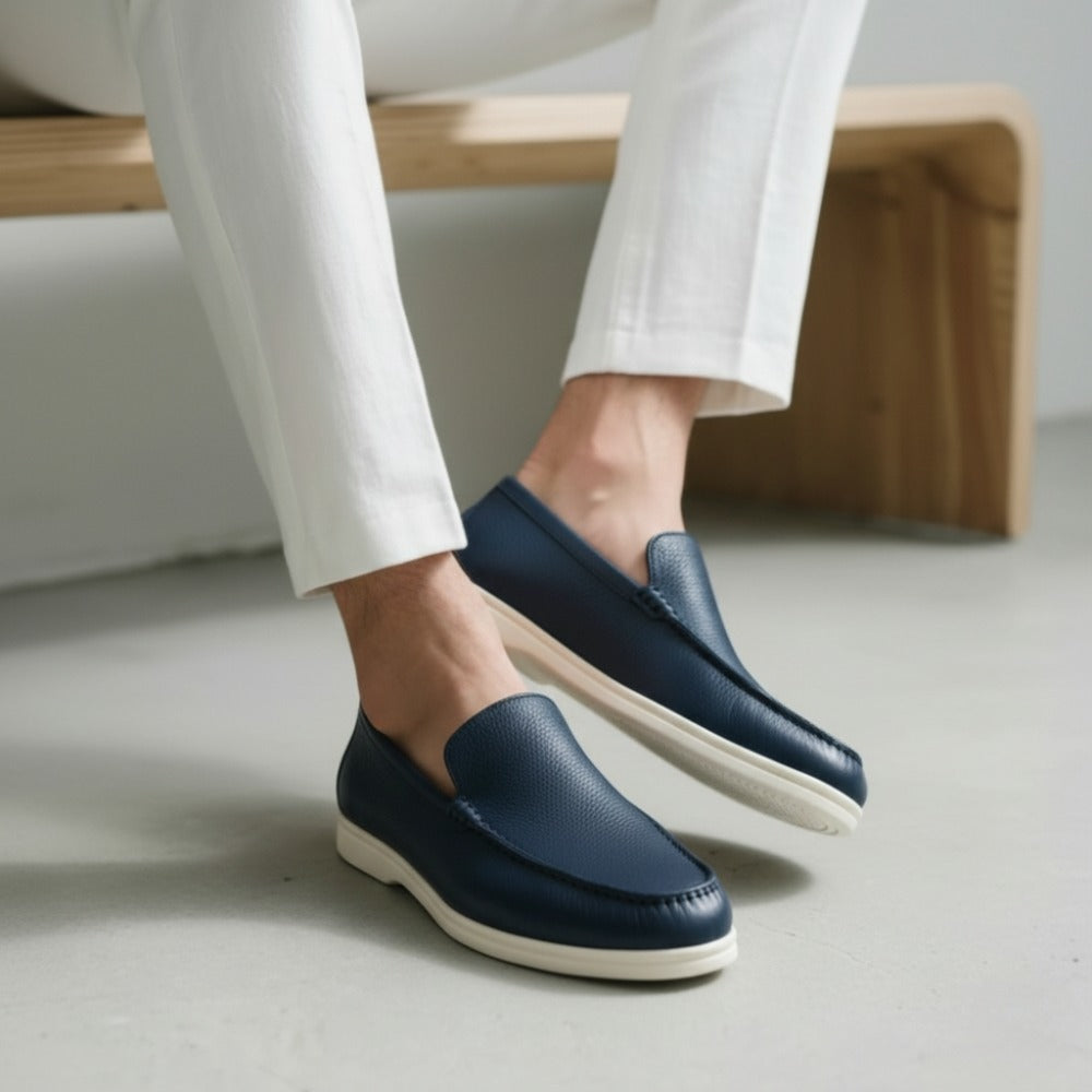Blue leather loafer by San Valier, shown with white soles and worn with white pants.
