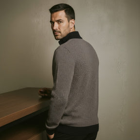 Gray knit quarterzip sweater by San Valier, with a textured pattern and black collar, worn by a man looking over his shoulder.
