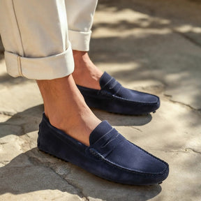 Navy suede driver loafers by San Valier, with tonal stitching and rubber pebble soles, worn with off-white cuffed trousers.